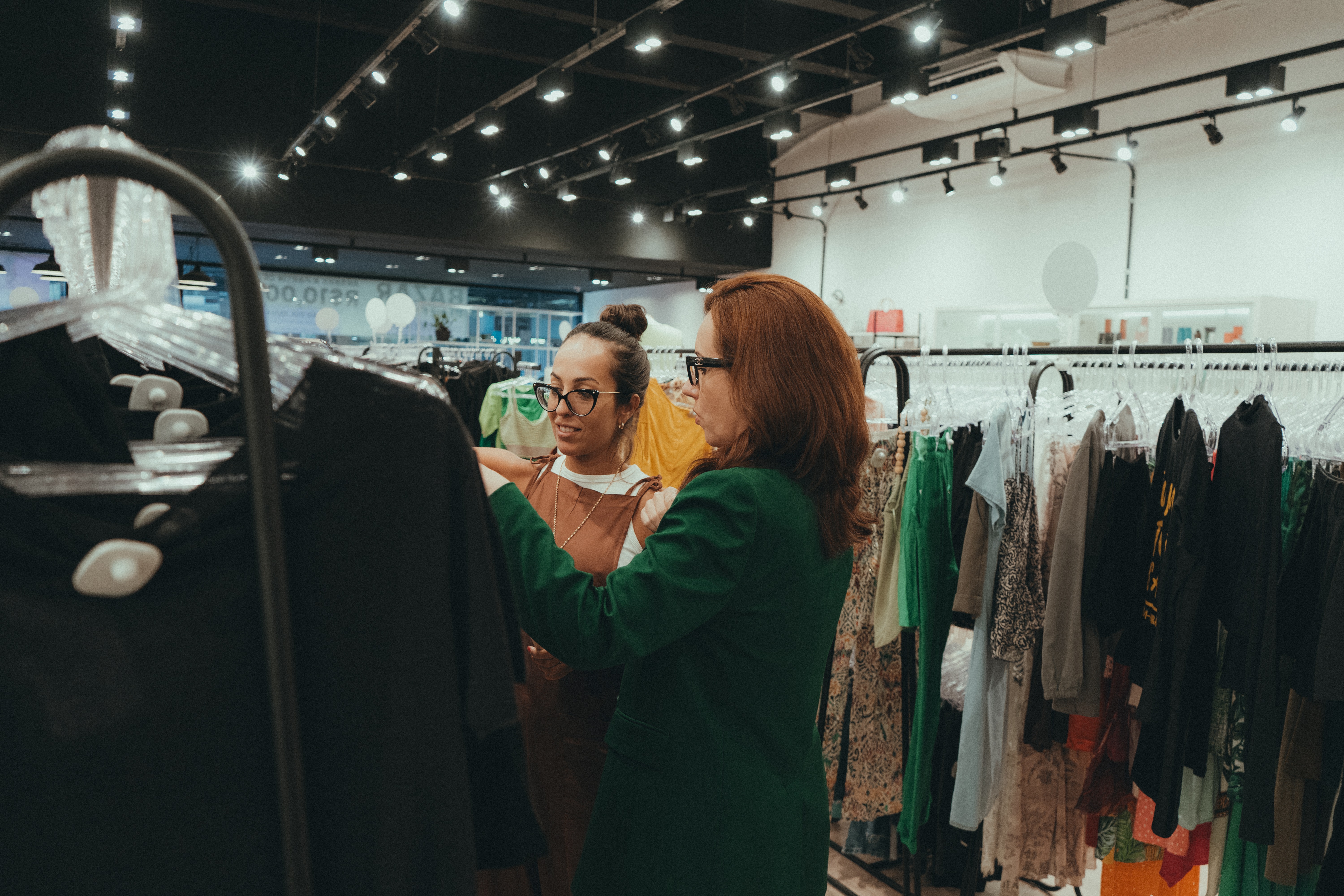 Clientes analisando roupas em loja