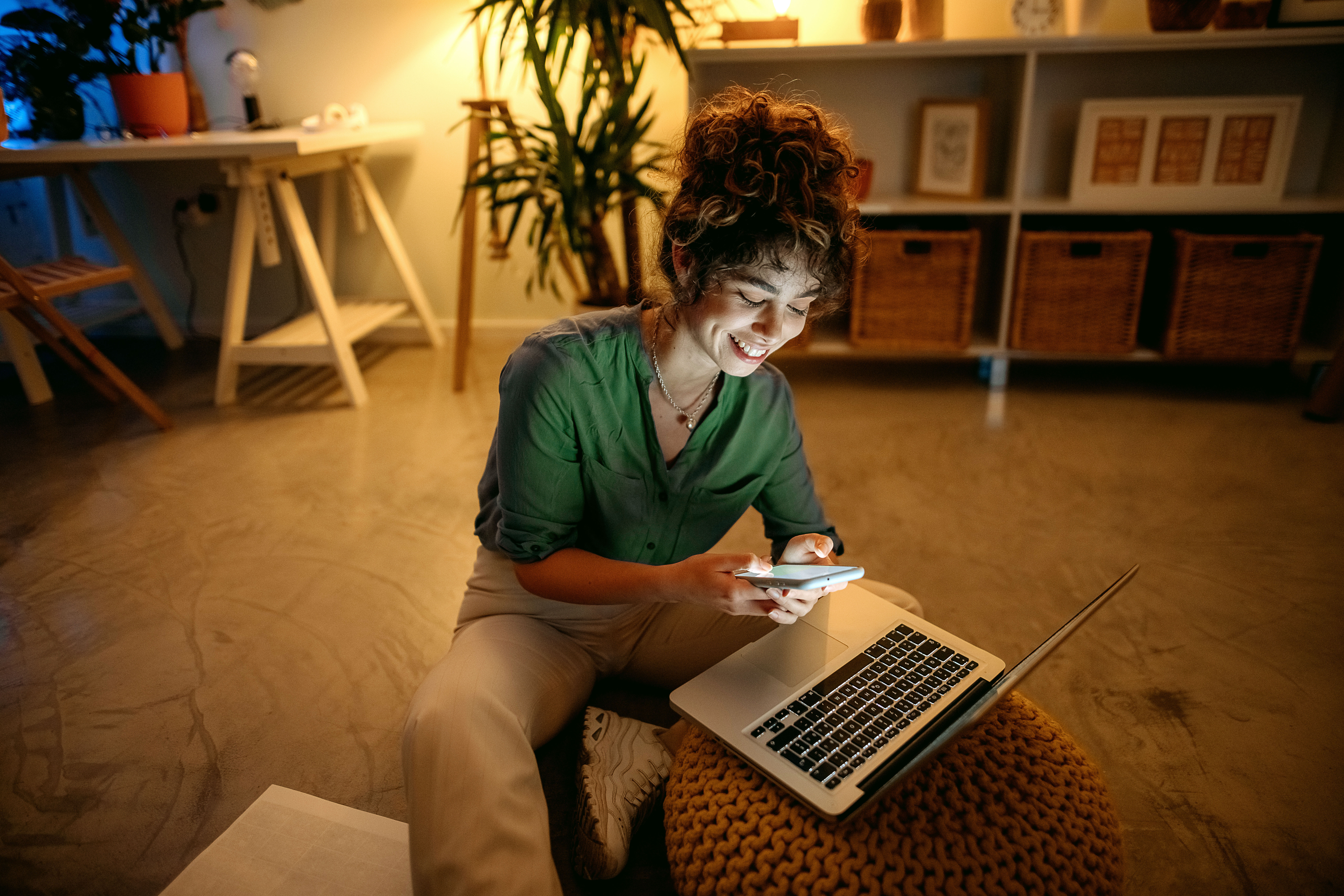 Mulher mexendo no celular e no computador para anunciar no Facebook