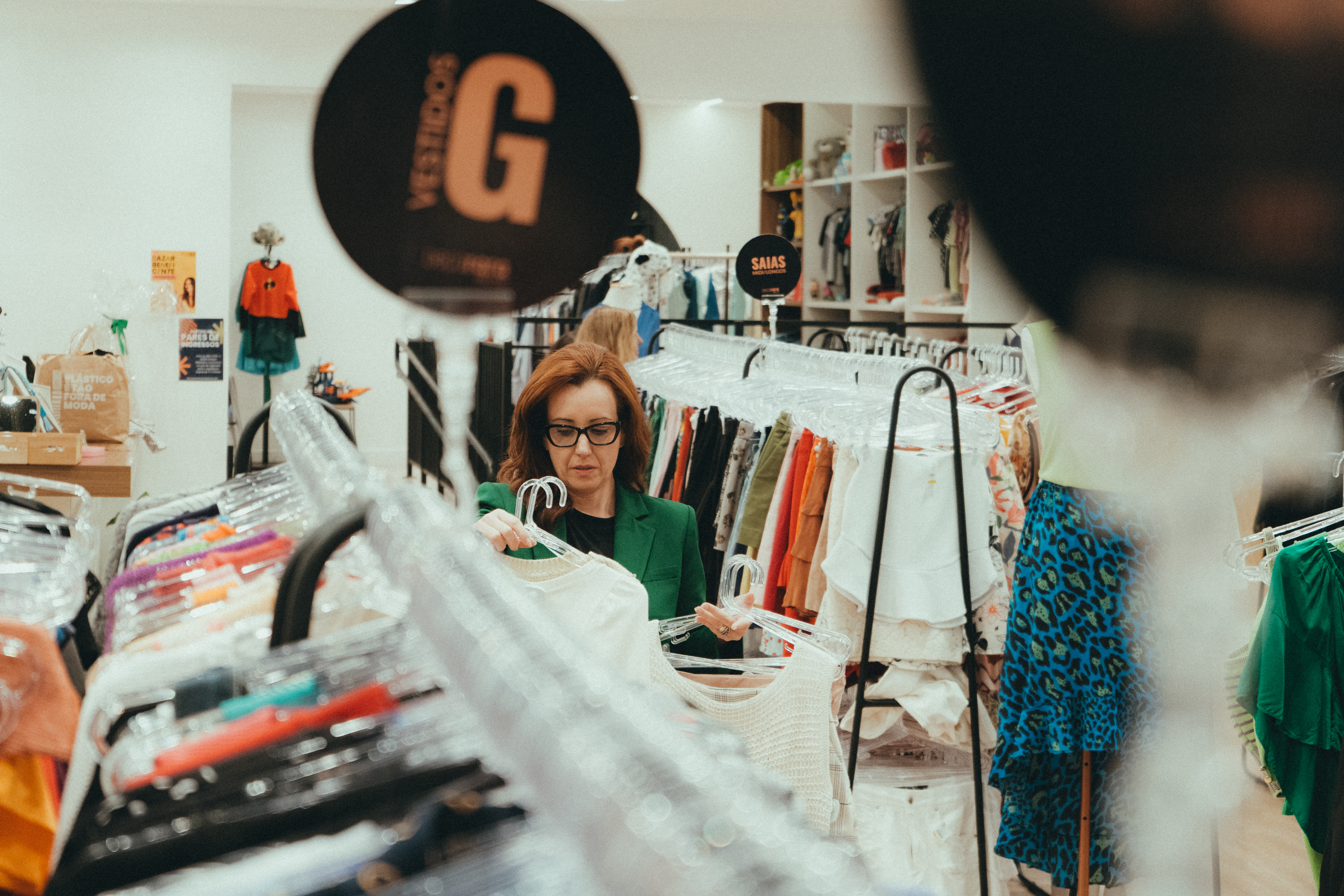 mulher mexendo em araras de roupas