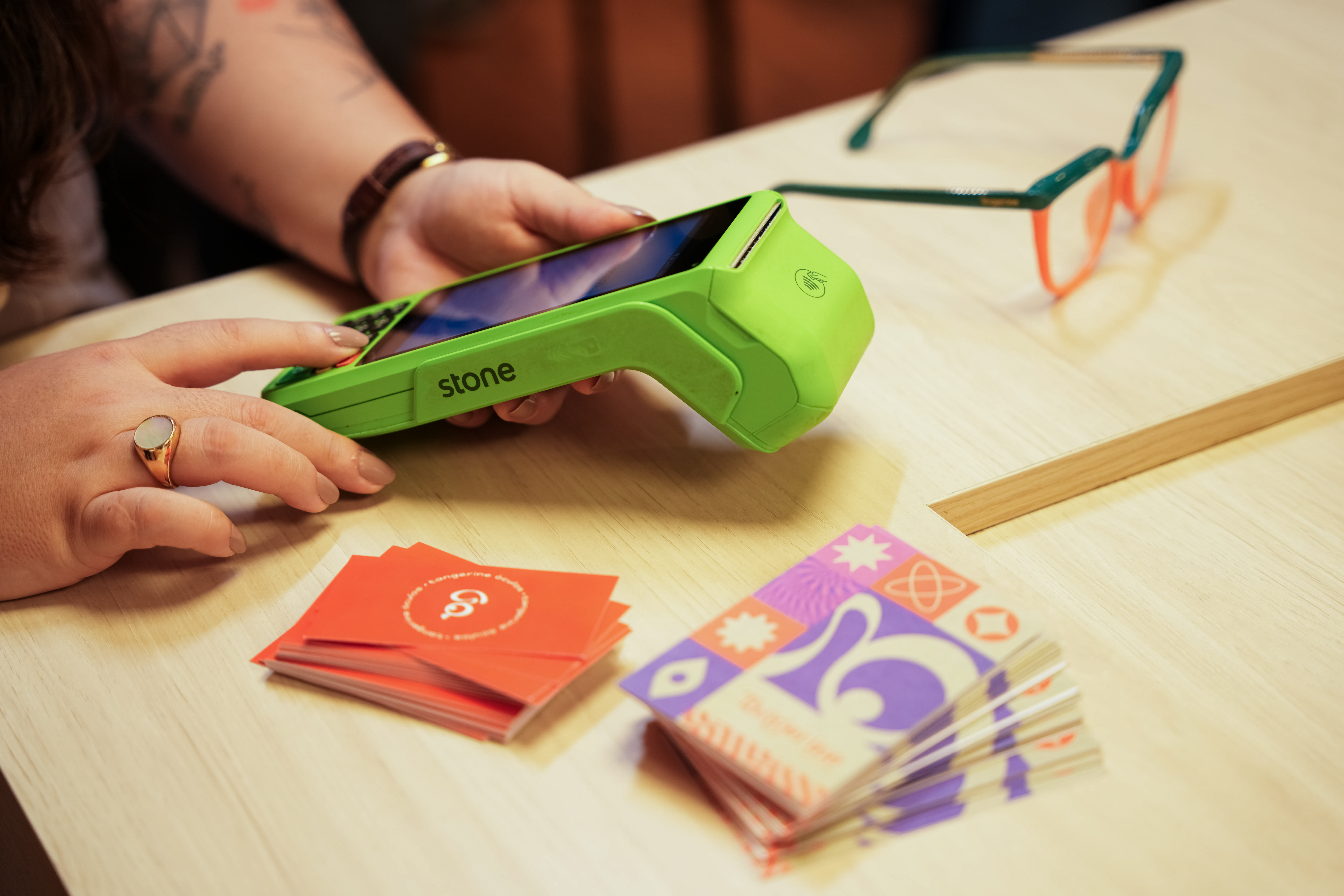 Lojista mexendo na maquininha de cartão da Stone em balcão