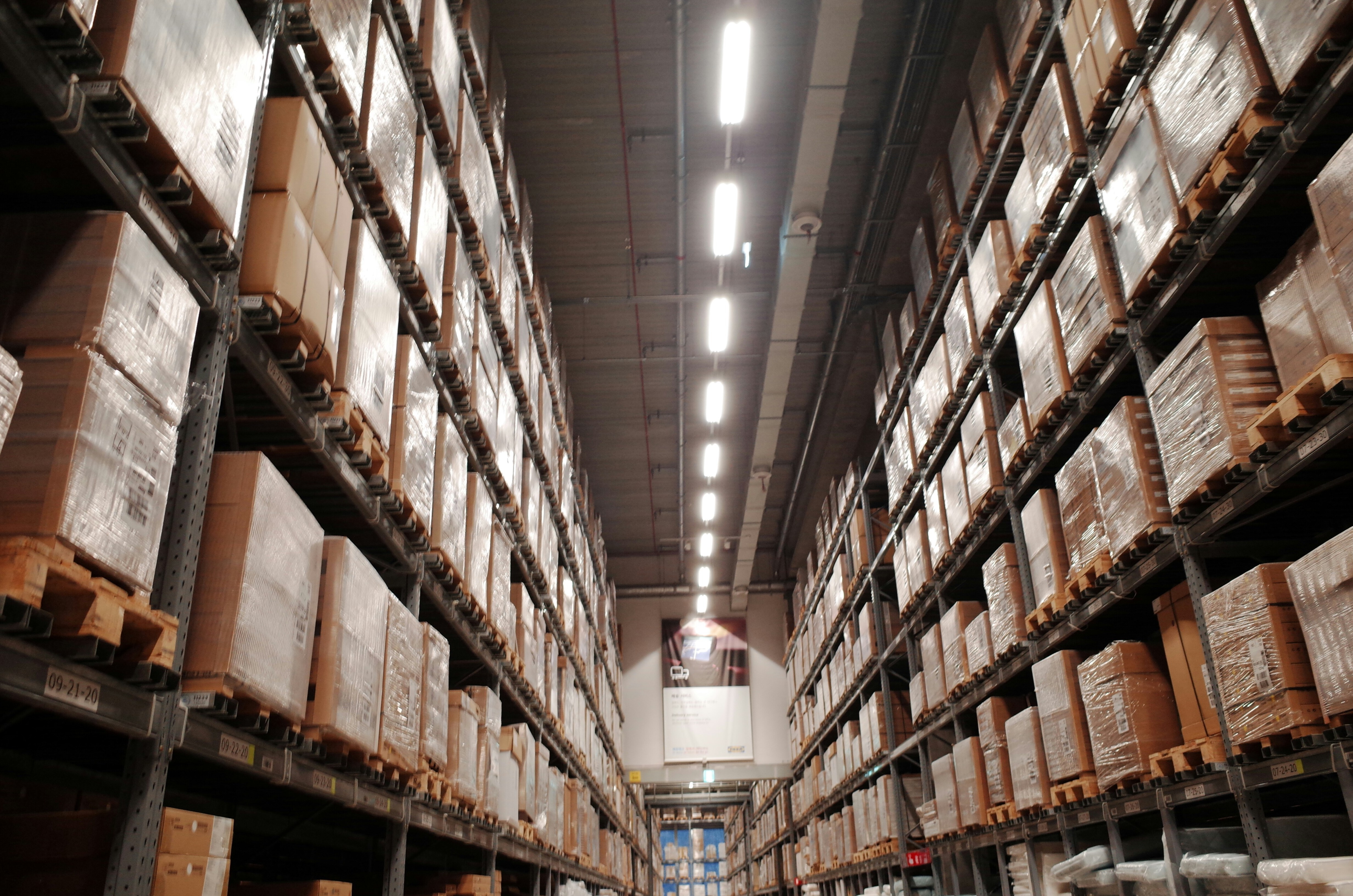 Na imagem é mostrado um depósito com muitas prateleiras armazenando caixas, como um centro logístico de uma empresa