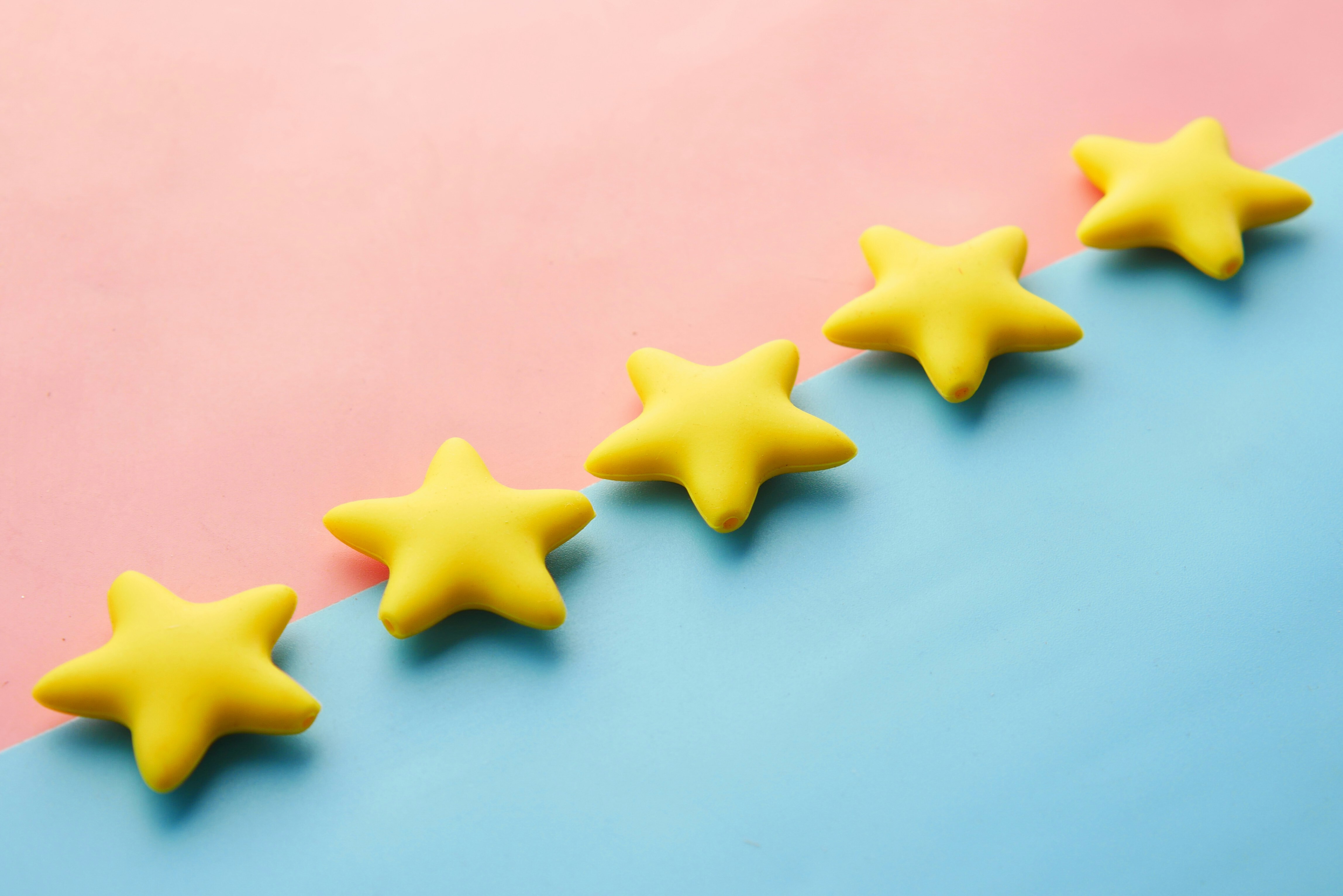 Imagem de 5 estrelas sobre um fundo azul e rosa, remetendo a avaliação como pesquisa de satisfação.