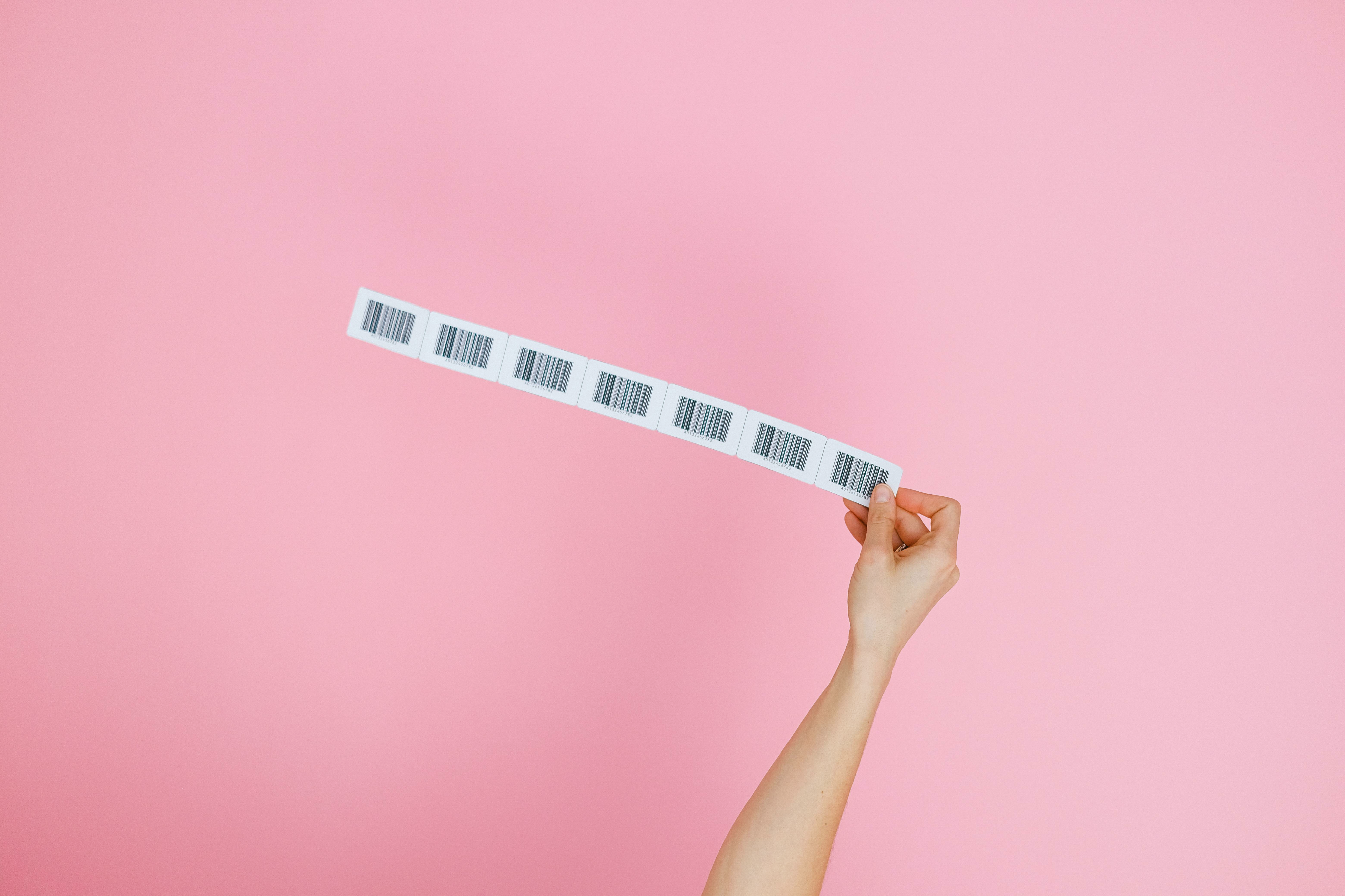 Imagem de uma mão feminina segurando uma tira de etiquetas de código de barras