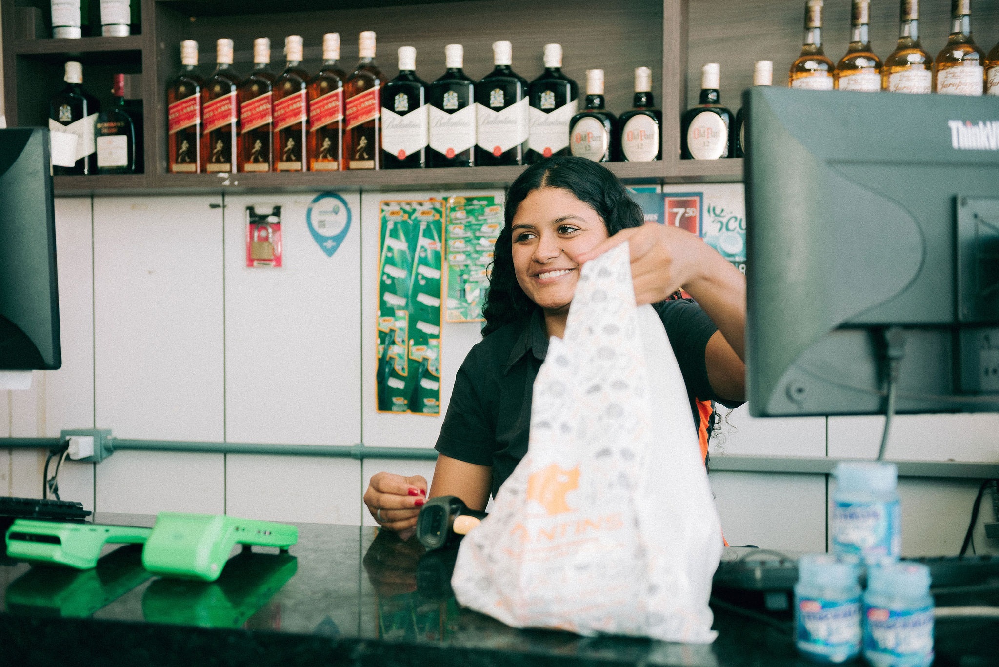 Vendedora entregando sacola de compras em mercearia