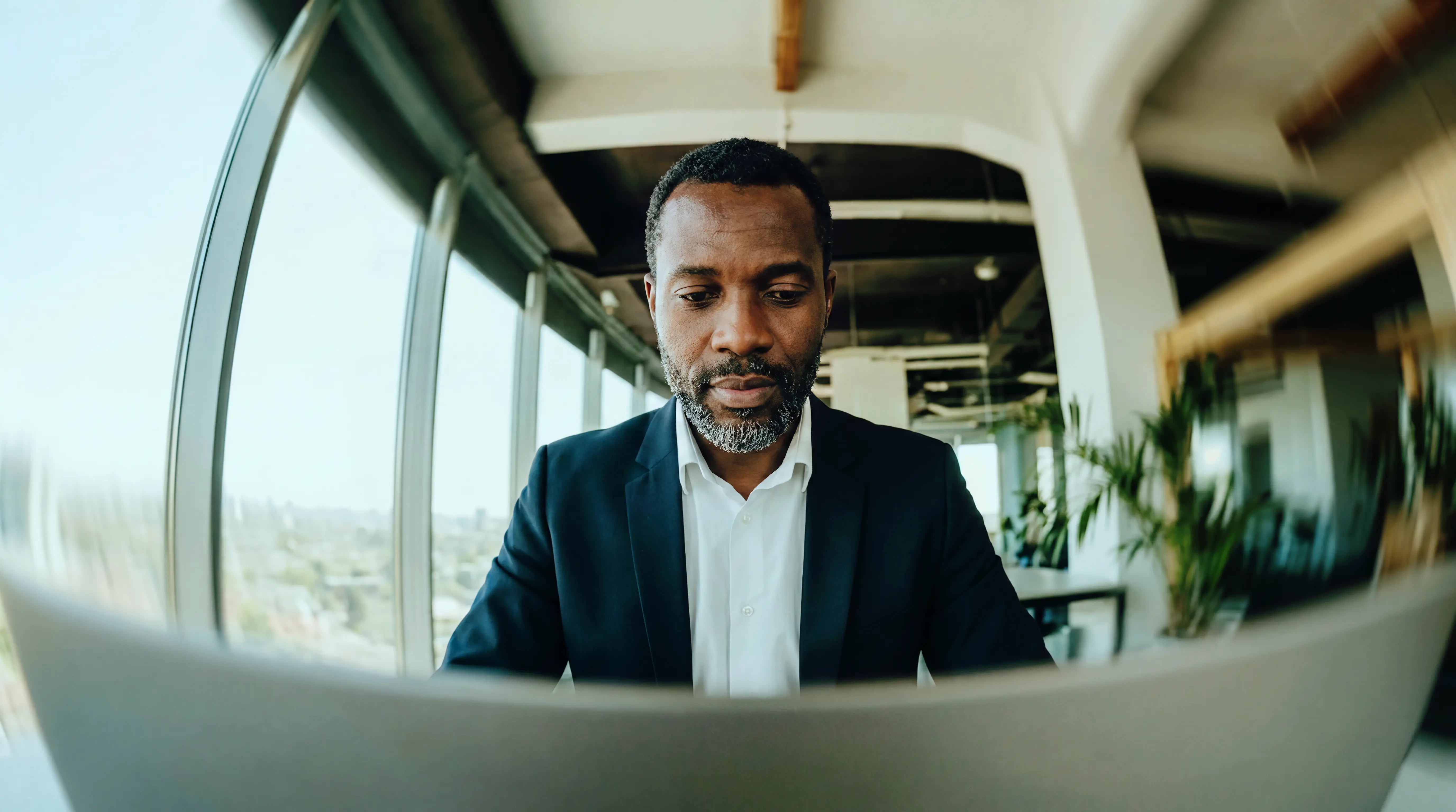 Homem estudando siglas corporativas no notebook em ambiente de trabalho