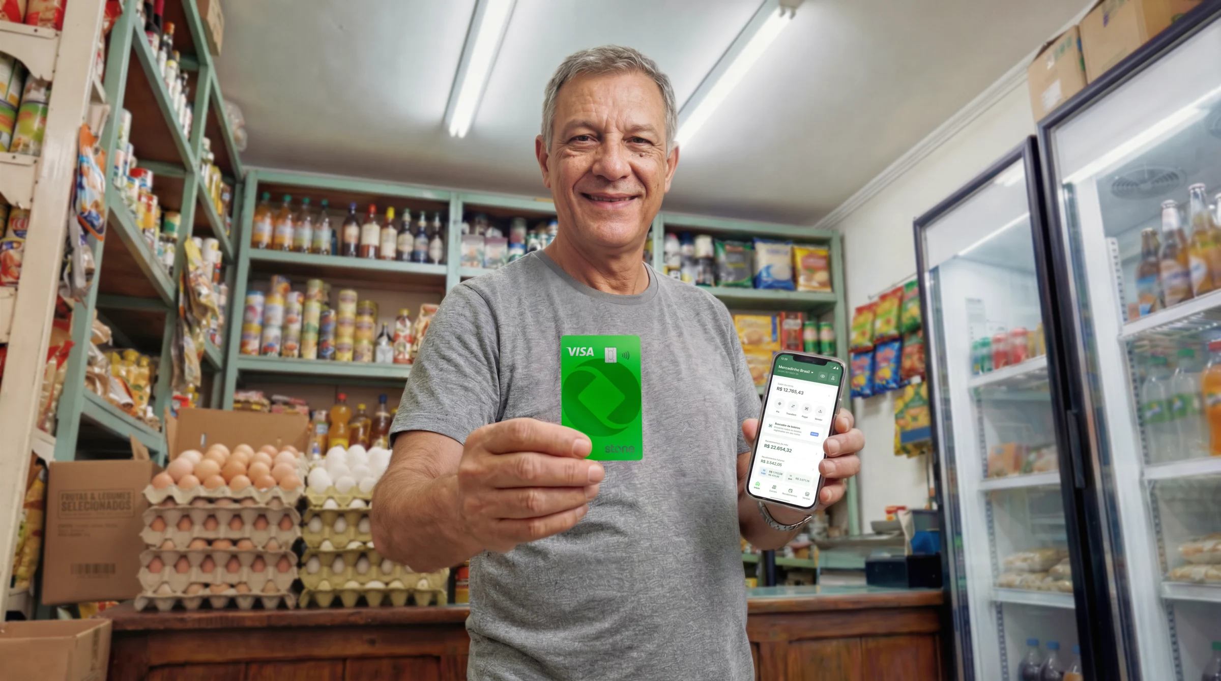 dono de loja sgurando cartao stone e celular